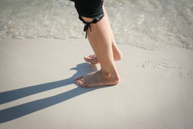 Kadın ayakları sahilde yürüyor 