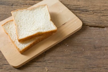 Sabah güneşi ve fotokopi alanı olan ahşap bir masada kahvaltı ekmeği.