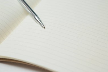 Pen 'in seçmeli odak noktası, beyaz arkaplan üzerine not defteri