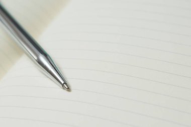 Pen 'in seçmeli odak noktası, beyaz arkaplan üzerine not defteri