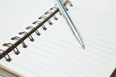 Pen 'in seçmeli odak noktası, beyaz arkaplan üzerine not defteri