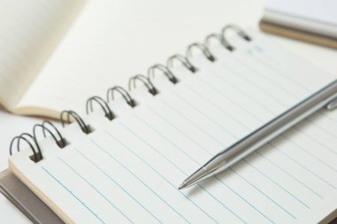 Pen 'in seçmeli odak noktası, beyaz arkaplan üzerine not defteri