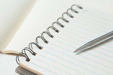 Pen 'in seçmeli odak noktası, beyaz arkaplan üzerine not defteri
