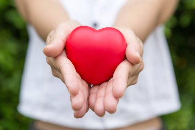 Bulanık arka planda elinde kalp şeklinde bir top olan bir kadının seçici odağı.