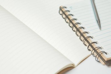 Pen 'in seçmeli odak noktası, beyaz arkaplan üzerine not defteri