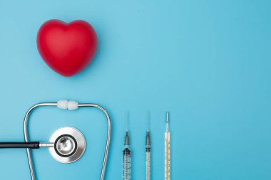 El kası egzersizi steteskop, şırınga ve termometre için kalp şeklindeki sıkıştırma topunun mavi arka planda üst görünümü ve kopyalama alanı
