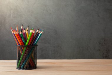 Kalem tutacağındaki renkli kalemler ahşap masalarda ve güneş ışığı ve yer kopyalayan tavan arası duvarlarında.