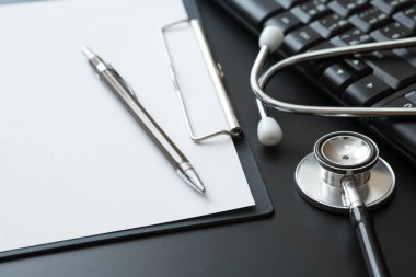 Stethoscope, Belge Tahtası, Klavye Bilgisayarı, Not Defteri, Siyah arkaplan üzerine Kalem ve Boşluğu Kopyala