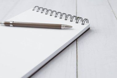 Kalem ve defterin beyaz tahta masa üzerindeki seçmeli odağı ve boşluğu kopyala