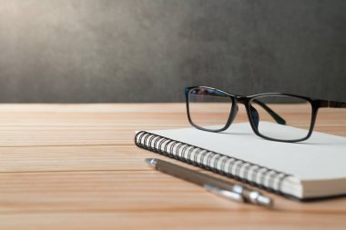 Defterler, kalemler, tahta masalardaki gözlükler ve güneş ışığı ve kopya alanı olan tavan arası duvarları.