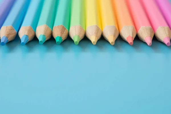 Colorful Pattern of Pastel colored pencils on blue background and copy space