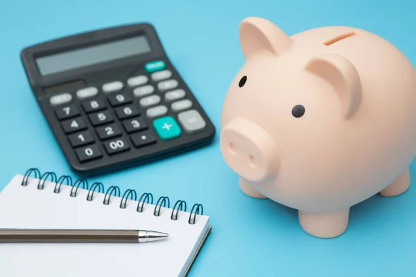 Defterler, kumbara, hesap makinesi, mavi arkaplanda kalemler ve boşluk kopyala