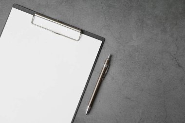 Gri arkaplan üzerindeki Belge Tahtası ve kalemin üst görünümü ve kopyalama alanı