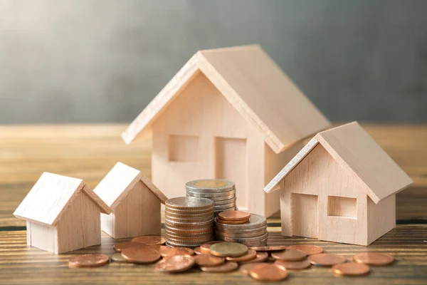 Model ev, madeni paralar ahşap masalara ve tavan arası duvarlarına yığılmış güneş ışığı ve para tasarrufu kavramı için kopyalama alanı