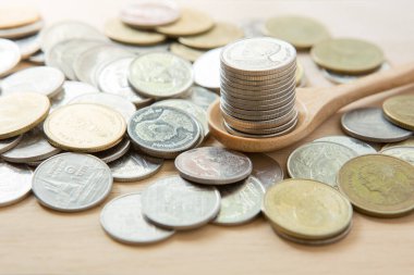 Para biriktirmek için güneş ışığıyla ahşap kaşığa istiflenmiş paralar.