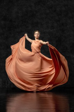 Ba -lerin. Uzun şeftali elbisesi giymiş genç bir dansçı, kurdeleli ayakkabılar. Zarif, zarif bir dans hareketi gerçekleştirir. Güzel klasik bale. Reklam bale stüdyosu. Volumetrik fotoğraflar
