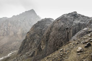 Gevşek taşlarla kaplı eğimli bir eğim. Aktru'ya zor tırmanış. Altay topraklarının doğasıbir tur yuvarlak dağların güzel manzarası. Yüksek piramidal dağ. Sibirya. Rusya.