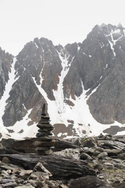 Altay Dağı. Cairn büyük bir dağın tepesinde. Sisli bulutlarda dağ zirveleri. Altay kara doğası ile turistik bir gezi yüksek karla kaplı dağların ve bir buzul güzel manzarası.