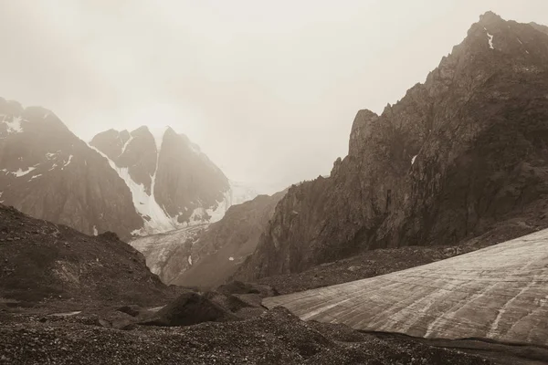 上面有大量的石头 雾云中的山峰 在阿尔泰陆地的自然之旅中 欣赏高雪覆盖的山脉和冰川的美丽景色 色调棕褐色照片 — 图库照片