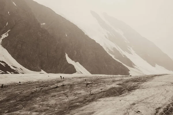 Buzulun eteklerinde alpenists vardır. Altay karlı dağların güzel doğası tonda fotoğraf. Küçük insanlar. Aktru Buzulu. Altay Dağı. Rusya. Tonda sepya fotoğraf