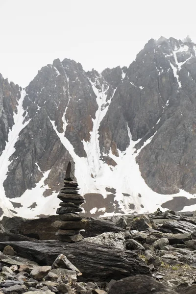 Altay Dağı. Cairn büyük bir dağın tepesinde. Sisli bulutlarda dağ zirveleri. Altay kara doğası ile turistik bir gezi yüksek karla kaplı dağların ve bir buzul güzel manzarası.