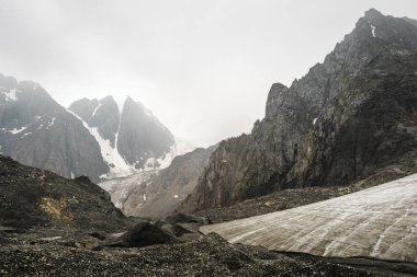 Altay Dağı. Üstünde çok sayıda taş var. Sisli bulutlarda dağ zirveleri. Altay kara doğası ile turistik bir gezi yüksek karla kaplı dağların ve bir buzul güzel manzarası.