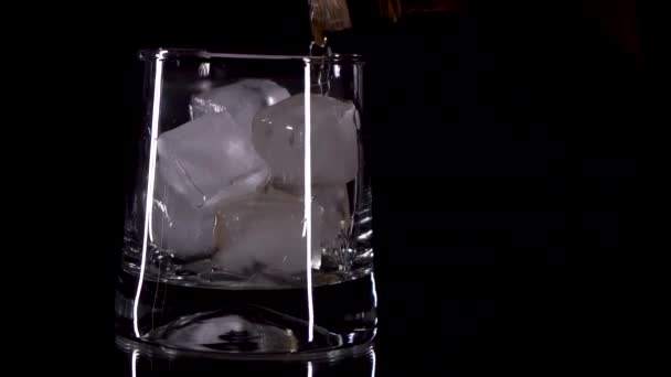 whiskyt öntenek egy pohár jég egy fekete háttér