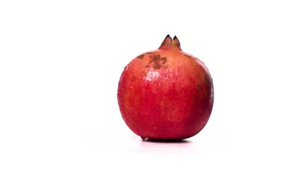 Zralé červené granátové jablko v kapkách vody se otáčí na bílém pozadí izolátu. Nádherná exotická bobule. Ovocné granátové jablko obsahuje mnoho vitamínů a je antioxidant pro zdravé a silné lidi.