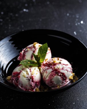 Siyah arka plan üzerinde ceviz ve nane ile siyah kase üç çilek dondurma topları