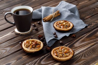 Ahşap bir arka plan üzerinde çay bir fincan yanında fındık ve bal ile Mini tart