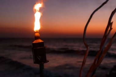 Bottle torch on the ocean at sunset clipart