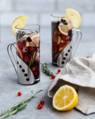 Kırmızı frenk üzümü, böğürtlen, limon, biberiye ve buz bej peçete, kırmızı frenk üzümü, biberiye ve limon kaplı açık gri arka plan ile lomonade iki bardak