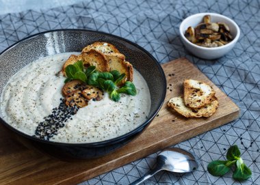 Kavrulmuş ekmek ve yeşillik ile süslenmiş mantar kremaçorbası ile kase ön görünümü