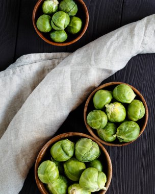 Çimenpe peçete ile çapraz koyu kahverengi odunsu arka plan üzerinde brüksel lahanası ile üç kase üst görünümü