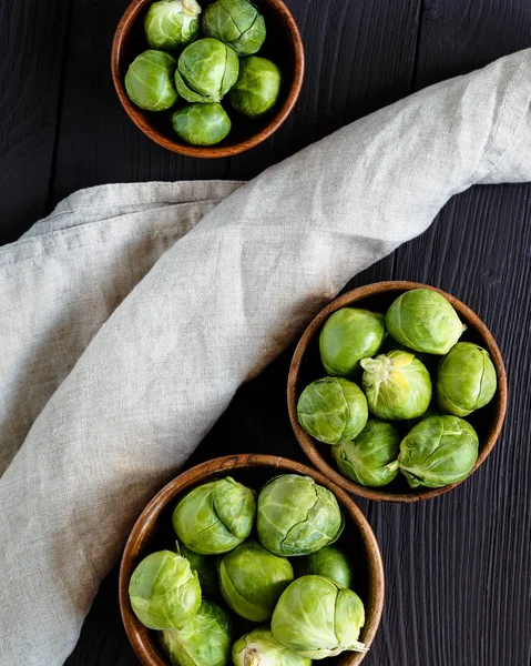 Çimenpe peçete ile çapraz koyu kahverengi odunsu arka plan üzerinde brüksel lahanası ile üç kase üst görünümü