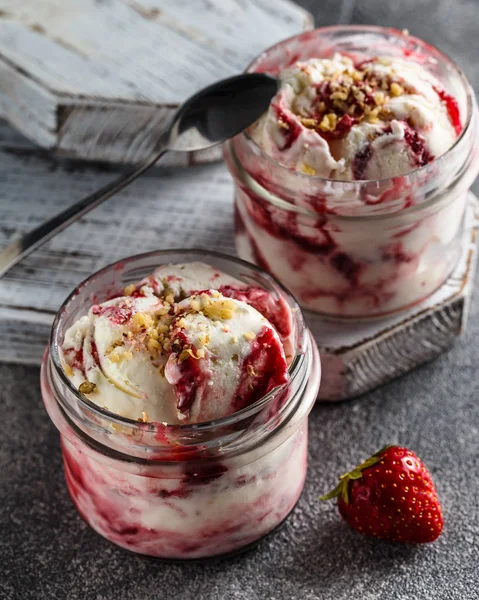 Two jars of strawberry ice cream on grey background