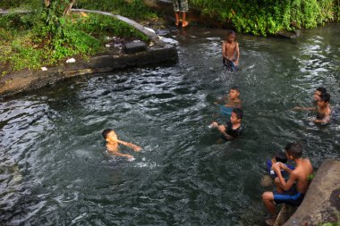 Yogyakarta, Endonezya - 28 Mayıs 2020: Çocuklar çok eğlenceli bir nehirde su oynayıp yüzüyorlar