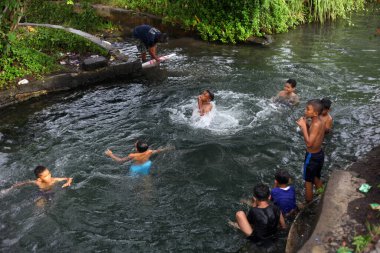 Yogyakarta, Endonezya - 28 Mayıs 2020: Çocuklar çok eğlenceli bir nehirde su oynayıp yüzüyorlar