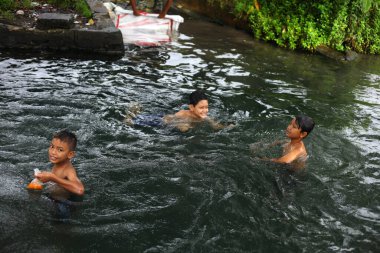 Yogyakarta, Endonezya - 28 Mayıs 2020: Çocuklar çok eğlenceli bir nehirde su oynayıp yüzüyorlar