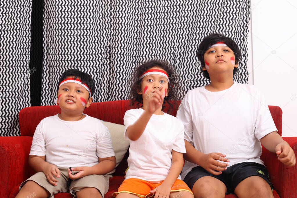 Cheerful expressions by wearing a red and white headband as a symbol of the Indonesian flag. The concept is watching television and giving support to the Indonesian team