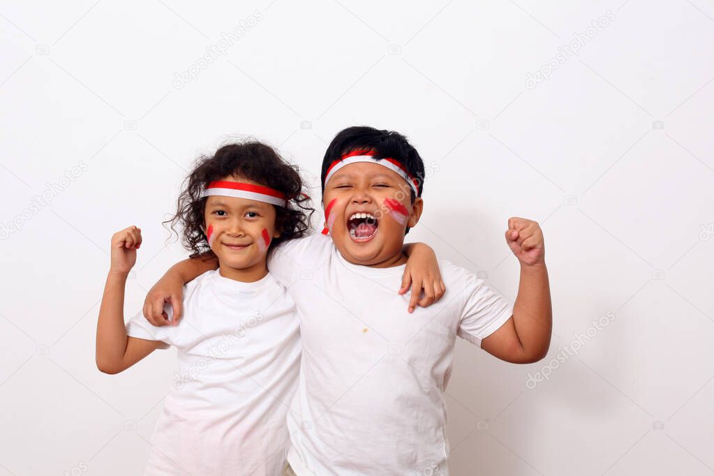 Adorable kids from indonesia celebrate indonesian independence day. Cheerful expressions by wearing a red and white headband as a symbol of the Indonesian flag against white wall