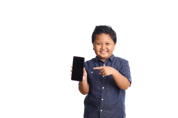 コピースペースのある白い背景に隔離された空白のスマートフォン画面を見せながら 青の愛らしいアジアの少年が立っています 選択的フォーカス — ストック写真
