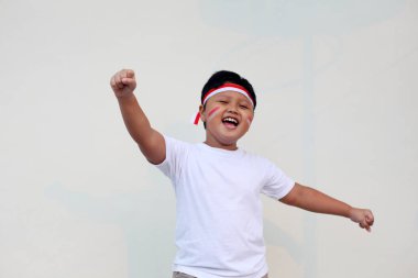 Endonezyalı sevimli çocuklar Endonezya 'nın bağımsızlık gününü kutluyorlar. Beyaz duvara karşı Endonezya bayrağının sembolü olarak kırmızı ve beyaz bir saç bandı takarak neşeli ifadeler