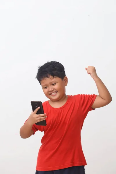 Menino Asiático Camisa Vermelha Feliz Enquanto Olha Seu Smartphone Isolado — Fotografia de Stock