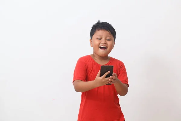 Азіат Червоній Сорочці Стоїть Щасливий Дивлячись Свій Смартфон Ізольований Білому — стокове фото