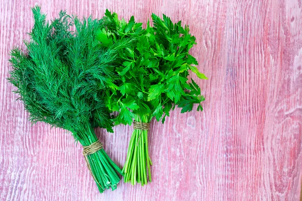 Twee trossen groene peterselie en dille op crarood rood getextureerde houten achtergrond. Horizontaal met kopieerruimte. Verse kruiden uit de tuin, gezonde groenten vol vitaminen. Veganistisch ingrediënt. Bovenaanzicht — Stockfoto