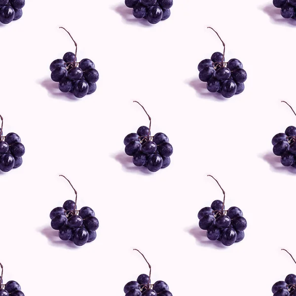 Modny bezszwowy wzór z małym gronem czarnych okrągłych winogron z cieniem na białym. Fotograficzny kolaż. Twórcze tło. Naturalne organiczne owoce. Zdrowe, słodkie i smaczne jedzenie. Odcień fioletowy. Obrazy Stockowe bez tantiem