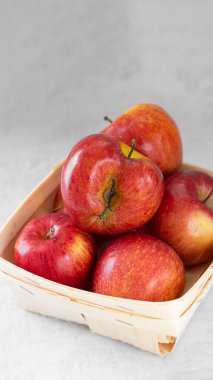 Üzerinde çirkin meyveler olan küçük ahşap bir şişede kırmızı taze organik elmalar. Gri çimento arka planında. Atıkları azaltmak için kusurlu ürün satın almak. Sürdürülebilir tüketim. Çevre trendi. Dikey pankart.