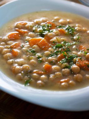 Yakından nefis vejetaryen, kalın çerez çorbası, beyaz tabakta corot ve yeşillikler. Türk ve Yunan mutfağı. Sağlıklı sebze yemeği. Dikey. Etli Nohut, Revithia yemeği.