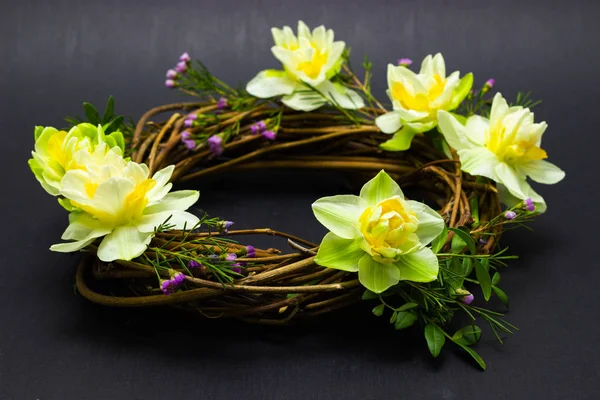 Wreath decorated with daffodils on a dark background — Stock Photo, Image